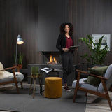 Element4 Summum 70 3S and a lady relaxing at the guess room with Real Flame Burner with True-to-Nature Wood Logs