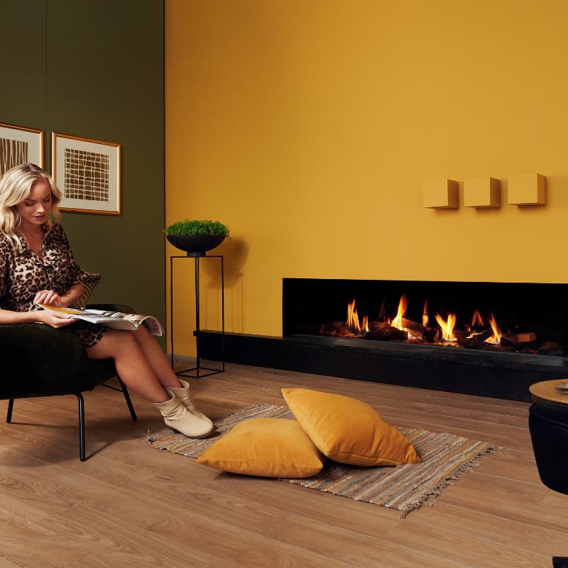 Element4 Summum 190 C with Real Flame Burner with True-to-Nature Wood Logs, Black Painted Steel Interior with Clean Face Design installed at the Guess room with a lady reading a book